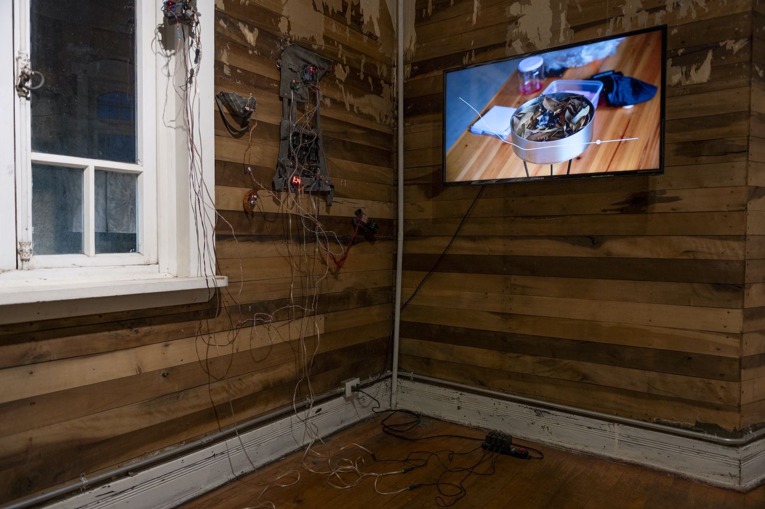 Part of the installations by Fernanda López de Quilodrán (left) and Valeria Palma (right) for the public residency program Bosque Pehuén – Ecologies of Fire presented at Casa Varas, a cultural center in Temuco, La Araucanía, April 2024. On the left, a suit that Fernanda wore in the forest to measure CO2 emissions; on the right, a video of Valeria measuring the ignition of native trees. Marcos Maldonado.